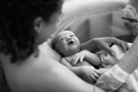 junge Mutter mit Neugeborenem im Arm